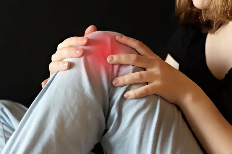 Female woman sitting down holding knee in pain