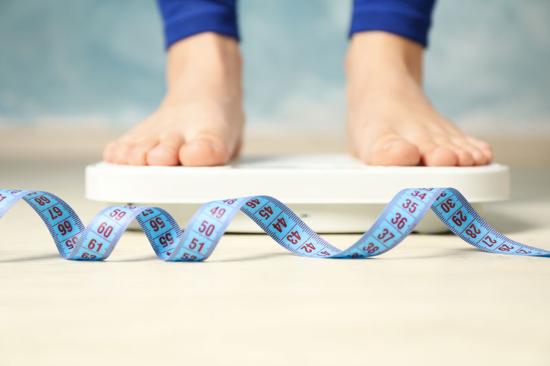 Woman stands on the scales Measuring tape Weight loss