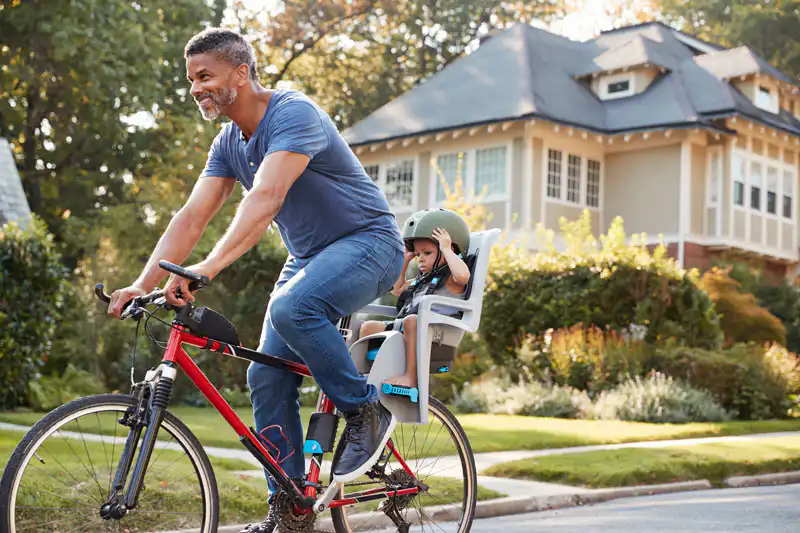 father cycling along street with daughter in child