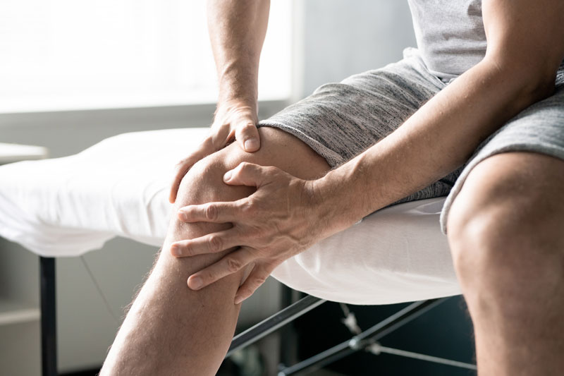 hands of contemporary mature man massaging right knee