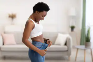 Black women looking at her stomach holding her jeans out