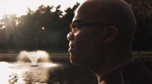 African American male in front of a pond looking forward
